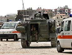 Soldados libaneses aguardam em veículo blindado ao lado de ambulância perto do campo