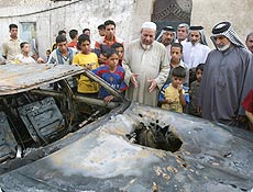 Moradores de Sadr City observa carro atingido por ataque areo dos EUA