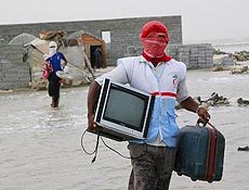 Homem retira objetos de regio inundada aps passagem do Gonu pelo sul do Ir