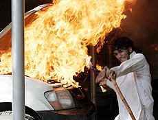 Estudante paquistans passa perto de chamas de carro no Ministrio do Ambiente
