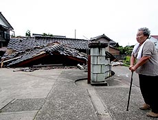 Mulher ao lado de casa destruda por dois terremotos seguidos que atingiram o Japo 