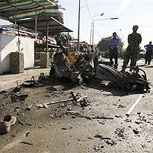 Pedestres observam veculo que explodiu em rea populosa de Bagd neste domingo