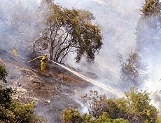 Bombeiro usa mangueira para apagar incêndio em Sierra Madre, sul da Califórnia