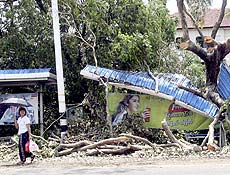 Garota mianmarense passa por ponto de ônibus atingido por árvore após passagem de ciclone