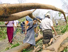 Moradores passam por árvore derrubada durante passagem de ciclone em Yangun