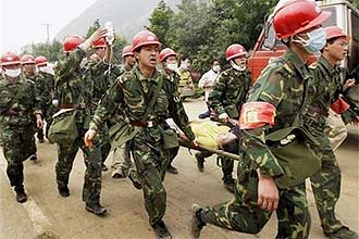 Soldados carregam mulher ferida na Provncia de Sichuan; temor dificultou trabalhos de resgate, segundo autoridades chinesas