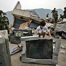 Soldiers help a shop owner to get his TV sets from his collapsed store in the village of Renhe near Shifang city west of Chengdu, Sichuan province, May 20, 2008. China raised the number of dead or missing from a devastating earthquake to more than 70,000 on Tuesday, as rescuers found another survivor eight days after the huge tremor hit. REUTERS/Bobby Yip (CHINA)