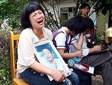 Mãe chora enquanto segura fotografia do filho, que morreu quando sua escola desabou