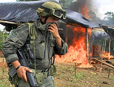 Membro da polícia antinarcótico cobre rosto durante queima de cocaína na Colômbia