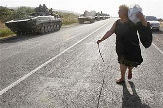 Mulher passa por tanques russos em estrada prxima  cidade georgiana de Igoeti, localizada a apenas cerca de 50 km de Tbilisi