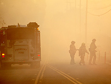 Firefighters walk through thick smoke as a brush fire burns near Carbon Canyon park in Brea, California November 16, 2008. Wildfires hop-scotched around Southern California on Sunday although calmer winds slowed flames that have destroyed almost 1,000 houses, forced tens of thousands to evacuate and turned some neighborhoods into scenes resembling war zones. REUTERS/Mario Anzuoni (UNITED STATES)