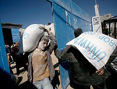 Palestinos recebem sacos da UNRWA com ajuda no campo de refugiados de Al Shatea
