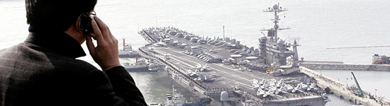 Homem observa navios dos EUA em exerccios militares conjuntos com Seul, testes ampliaram tenso