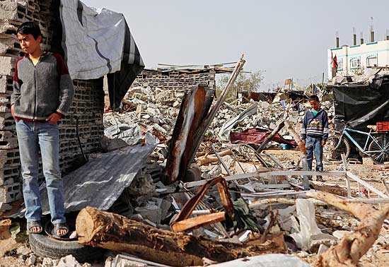 Garotos palestinos passam por escombros prximos ao local onde sua casa foi destruda, durante a ofensiva