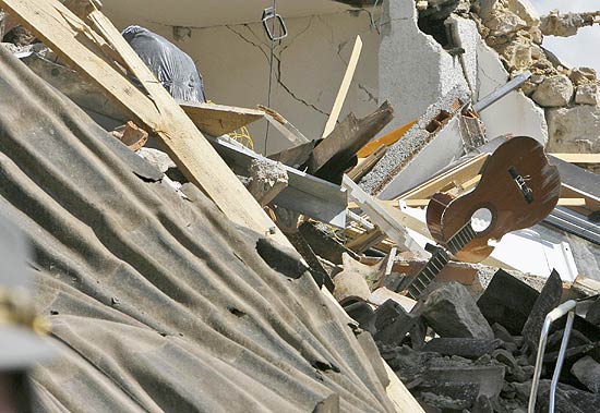 Imagem mostra violo destrudo em meio a escombros de um edifcio de quila, atingida por novos tremores nesta tera