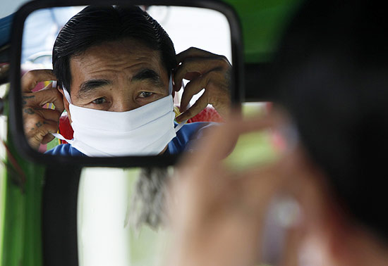 Motorista de táxi usa máscara para evitar contaminação com a gripe suína em Bancoc, capital da Tailândia