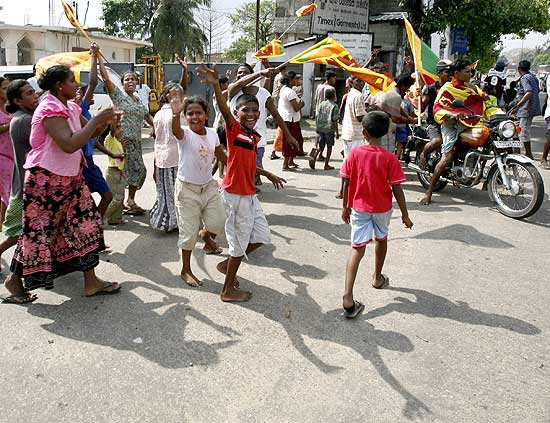 Cingaleses levam bandeiras do país em comemoração à vitória do Exército sobre os rebeldes separatistas tâmeis 
