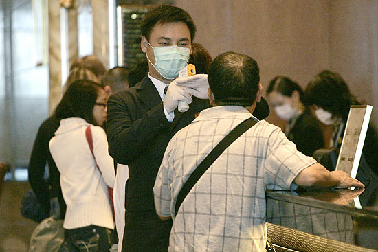Funcionário de hotel checa temperatura de turista antes do procedimento de check-in em Hong Kong, na China 