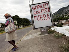 Mulher passa por placa pedindo a sada do interino Roberto Micheletti, em Tegucigalpa