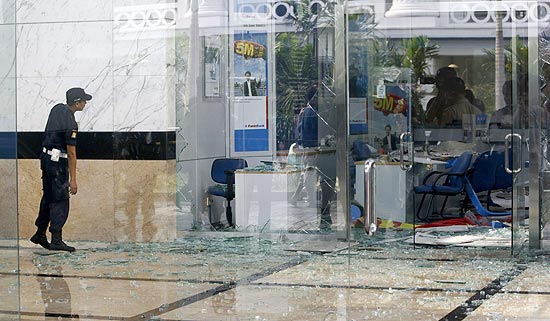 Segurana passa por vidraa destruda do hotel de luxo JW Marriott; ataque coordenado deixou nove mortos