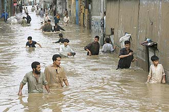 Homens caminham em ruas completamente alagadas pelas fortes chuvas em Karachi, uma das principais cidades do Paquisto