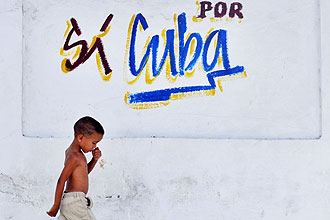 Menino caminha diante de grafite que diz "sim por Cuba", em Havana; país passa por grave crise e teve de cortar importações