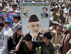 Jovens afegos seguram cartaz do presidente Hamid Karzai em comcio eleitoral em Jalalabad