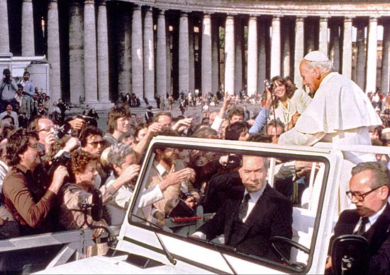 Joo Paulo 2 passeia na praa de So Pedro momentos antes do atentado que sofreu no dia 13 de maio de 1981;  esquerda, em meio  multido, criminoso aponta arma antes de disparar