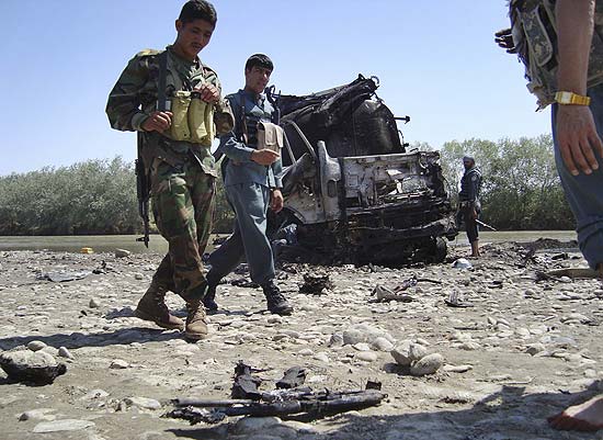 Policiais afegos observam rifles queimados durante incndio causado por bombardeio areo da Otan