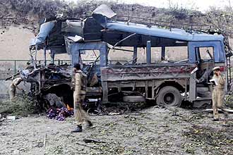 Policiais indianos e soldados paramilitares observam nibus destrudo por exploso de carro-bomba em Srinagar, na Caxemira indiana 