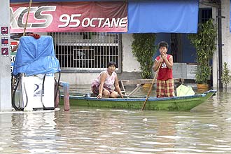 Moradores usam canoa para se locomover por ruas inundadas em Ondoy, nas Filipinas, tempestade Ketsana matou 140 