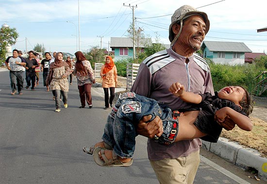 Homem corre com seu filho nos braos em Ule Lhuee em uma simulao contra tsunamis na Indonsia