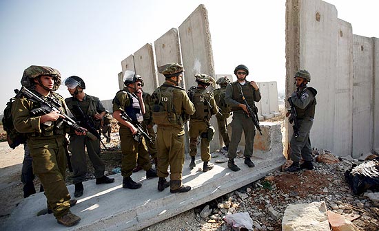 Israelenses vigiam barreira em Kalandia, na Cisjordânia, após palestinos terem derrubado pedaço de muro judaico