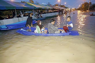 Famlia cruza rua inundada pelas chuvas de mones na Provncia de Pattani, no sul da Tailndia; ao menos 18 morreram 