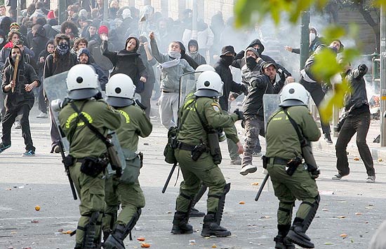 Jovens lanam objetos contra a polcia local no segundo dia de violentos confrontos em Atenas, capital da Grcia
