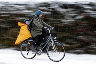 Mulher leva criana em bicicleta na Inglaterra; nevasca fecha escolas e aeroportos e deixa centenas presos em carros 