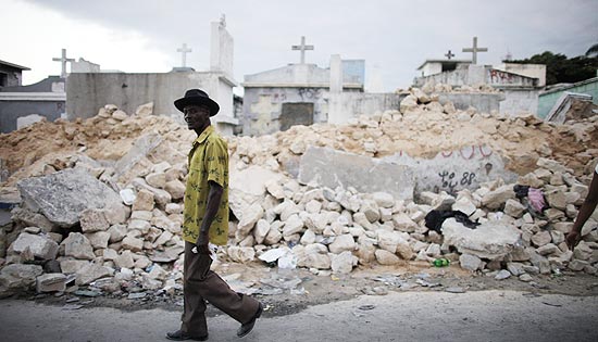 Homem passa por cemitério destruído por terremoto em Porto Príncipe; Haiti enterrou 7.000 em vala comum 