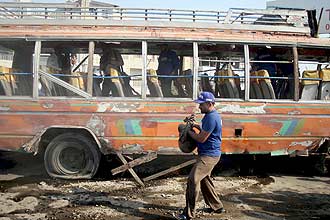 Membro das foras de segurana paquistanesas avalia os restos de nibus com xiitas atingido por bomba em Karachi
