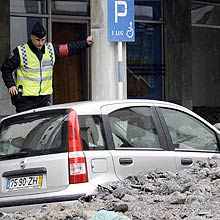 Policial observa carro coberto por pedras após inundações em  Funchal, Ilha da Madeira 
