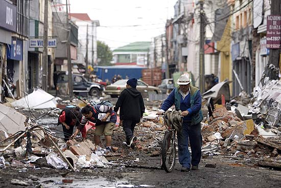 Pessoas recolhem objetos que sobreviveram ao terremoto nas ruas de Talcahuano, no Chile