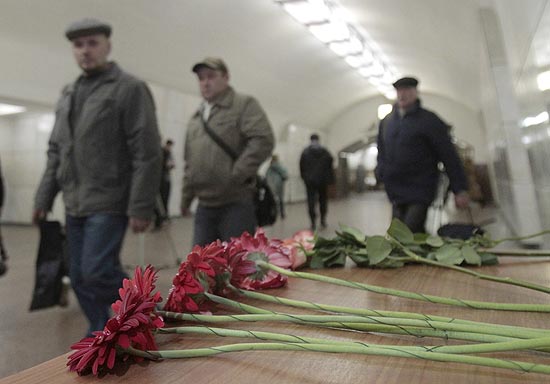 Pessoas passam por flores deixadas em memória das 38 vítimas dos ataques a duas estações de metrô de Moscou