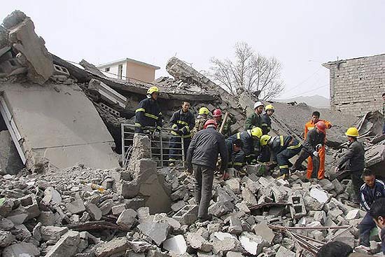 Equipes de resgate procuram por sobreviventes em meio aos escombros de um prédio em Yushu, na China