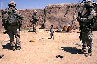 Criança observa militares americanos em área residencial na Província de Helmand; soldados morrem cada vez mais jovens