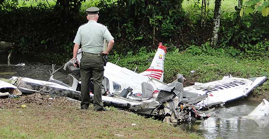 Policial observa os restos do avião monomotor que caiu perto de Villavicencio nesta quarta-feira, matando dois