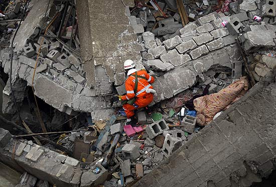 Membro da equipe de resgate procura sobreviventes nos escombros de um prdio que desmoronou em Yushu