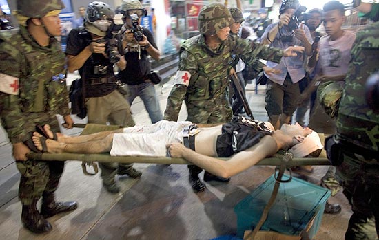Paramédicos levam a australiana Ben Rown para uma ambulância após série de explosões em Bancoc