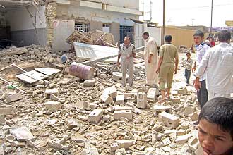 Iraquianos observam danos causados por bombas detonadas em casas de policiais em Fallujah, 65 km a oeste de Bagd, no Iraque