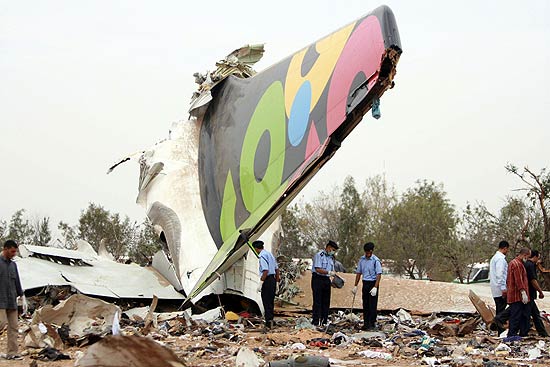 Equipes examinam um dos maiores pedaos da fuselagem do avio da Afriqiyah Airways, que caiu ao pousar