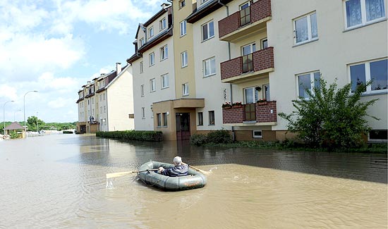 Homem atravessa rua inundada em bote na Polnia; enchentes matam 15 e isolam milhares
