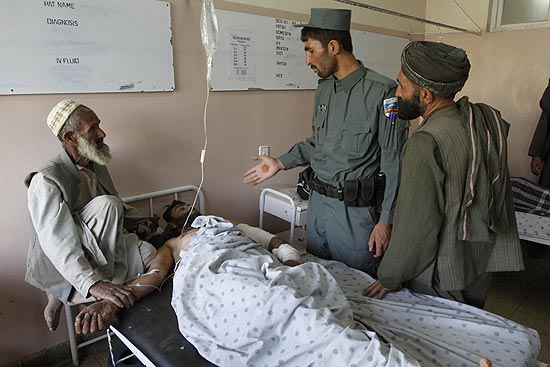 Polciais interrogam uma das vítimas do ataque que deixou ao menos 40 mortos num casamento em Candahar
